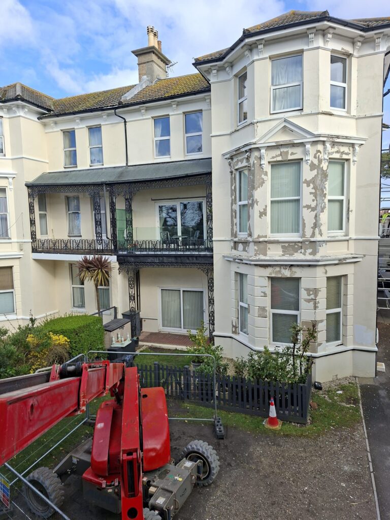 Block of flats in Boscombe before exterior painting showing peeling masonry paint and access equipment in place